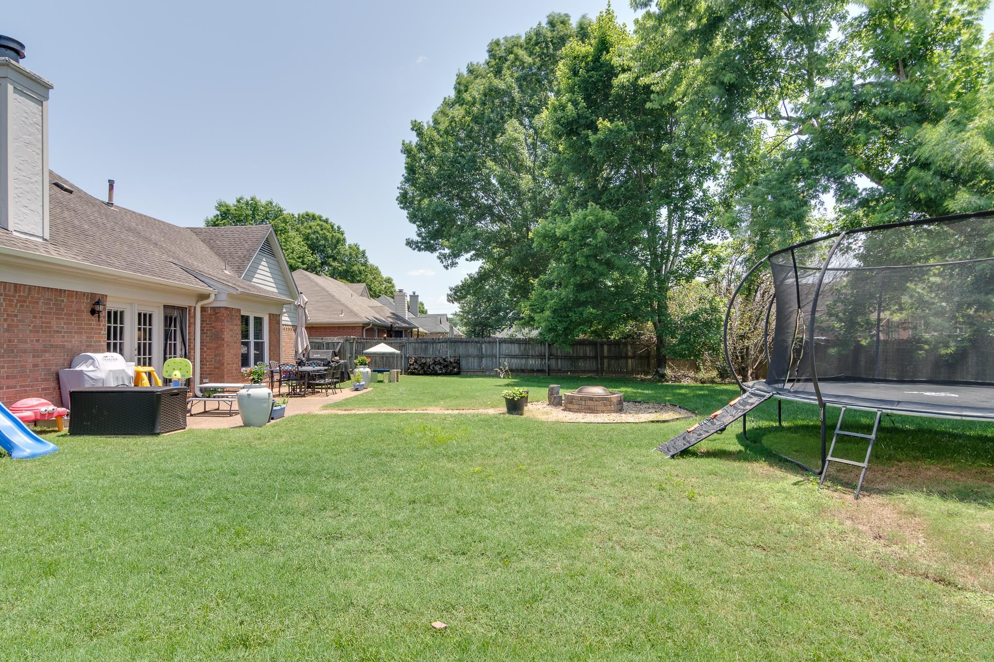 8703 Old River Road Memphis, TN 38018 - Photo 27 of 31 Fenced backyard featuring a trampoline, a fire pit, and a patio