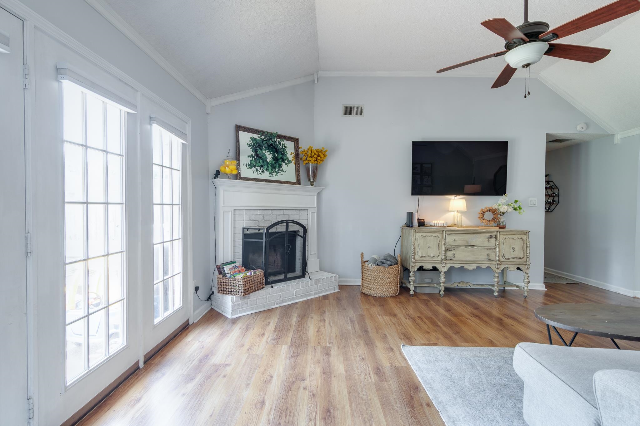 8703 Old River Road Memphis, TN 38018 - Photo 8 of 31 Living room featuring vaulted ceiling, a brick fireplace, wood finished floors, a ceiling fan, and crown molding