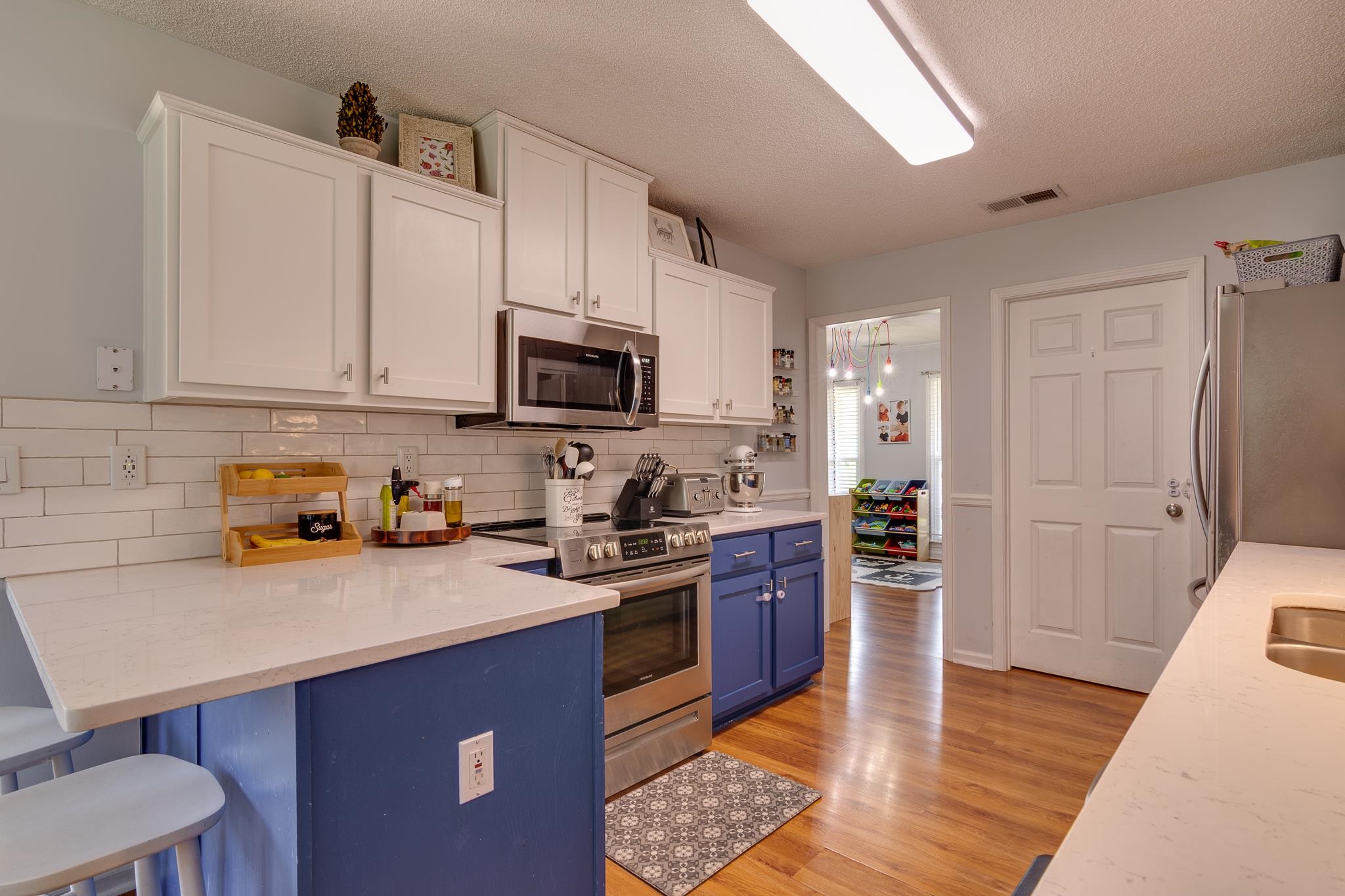 8703 Old River Road Memphis, TN 38018 - Photo 10 of 31 Kitchen featuring stainless steel appliances, blue cabinets, white cabinets, light wood finished floors, and a textured ceiling