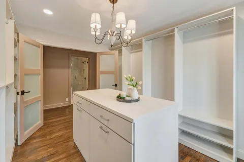 a view of a hallway with wooden floor and chandelier