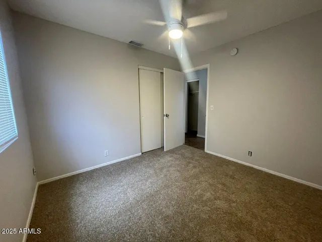 an empty room with a ceiling fan and window