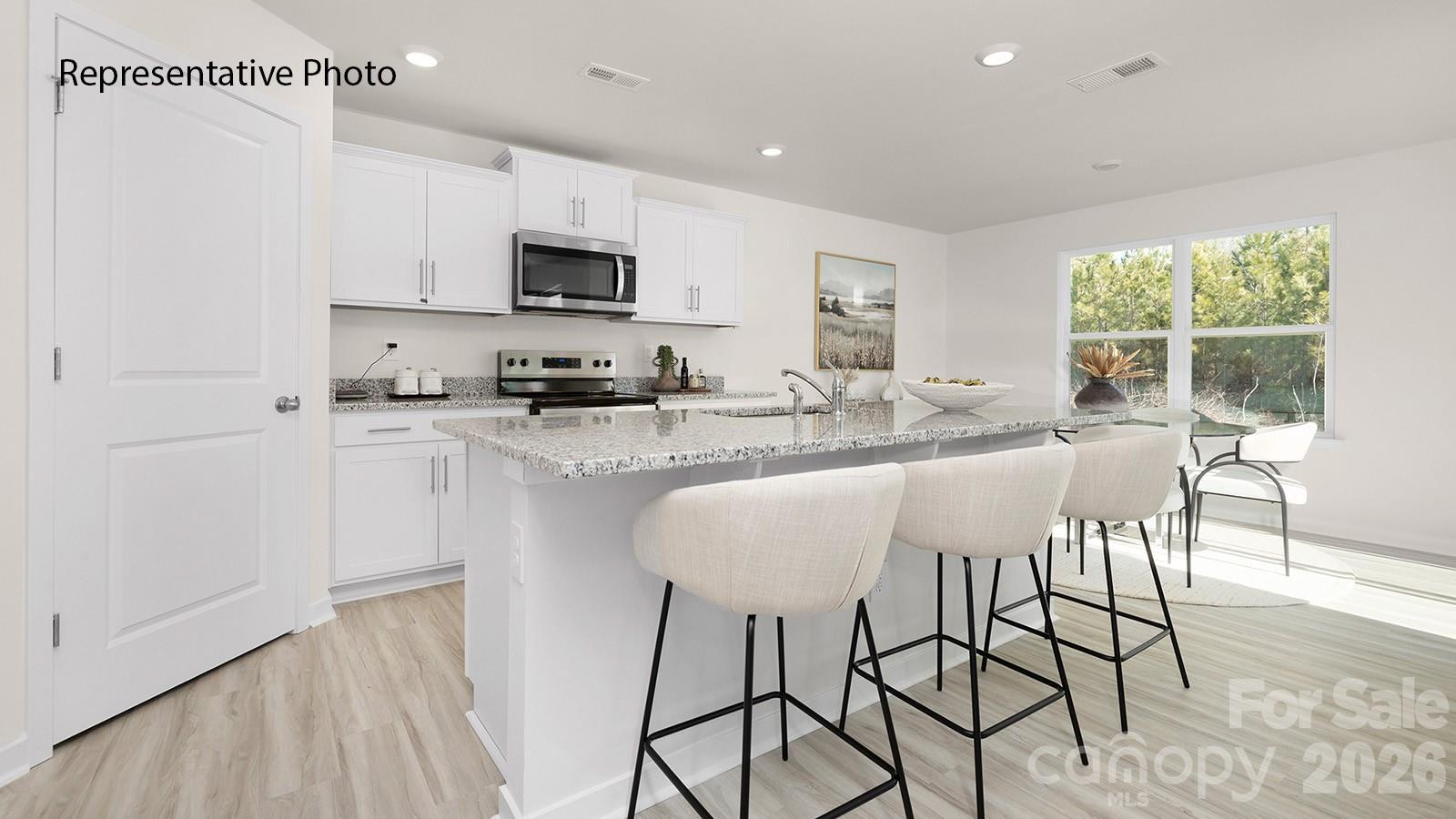560 North Sparkleberry Street Chester, SC 29706 - Photo 3 of 21 a kitchen with stainless steel appliances granite countertop a stove top oven a sink a refrigerator and white cabinets with wooden floor