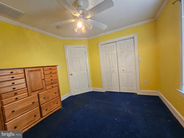 a spacious bedroom with a bed a dresser and paintings on the wall