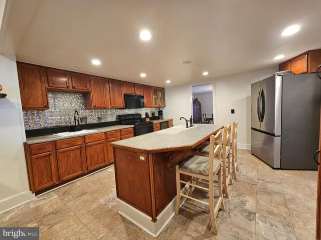 a kitchen with stainless steel appliances granite countertop a table chairs sink refrigerator and microwave