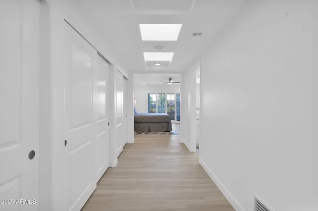 a view of a hallway with wooden floor and a bathroom