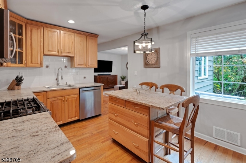 3 Maple Way Mountain Lakes, NJ 07046 - Photo 5 of 28 a kitchen with stainless steel appliances granite countertop a stove a sink dishwasher a dining table and chairs with wooden floor