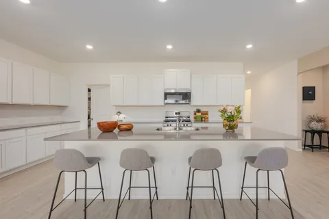 a kitchen with stainless steel appliances kitchen island granite countertop a dining table chairs and white cabinets