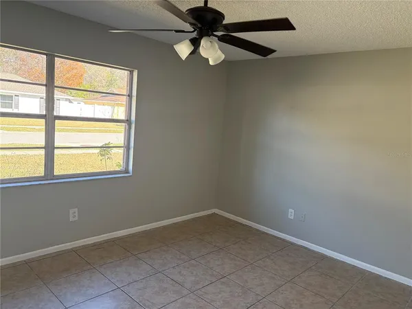 an empty room with a window and a fan