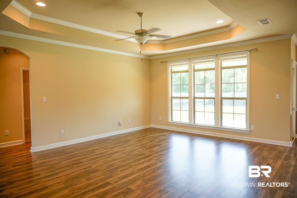 593 Begeman Road Mobile, AL 36608 - Photo 7 of 23 Empty room featuring ceiling fan, a raised ceiling, dark hardwood / wood-style flooring, and crown molding