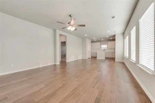 a view of empty room with wooden floor and fan