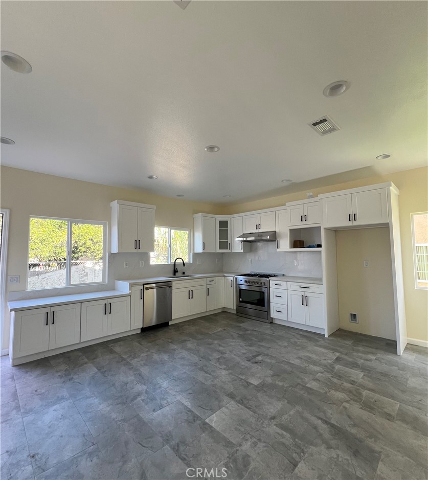 a large kitchen with stainless steel appliances cabinets a sink and a large window