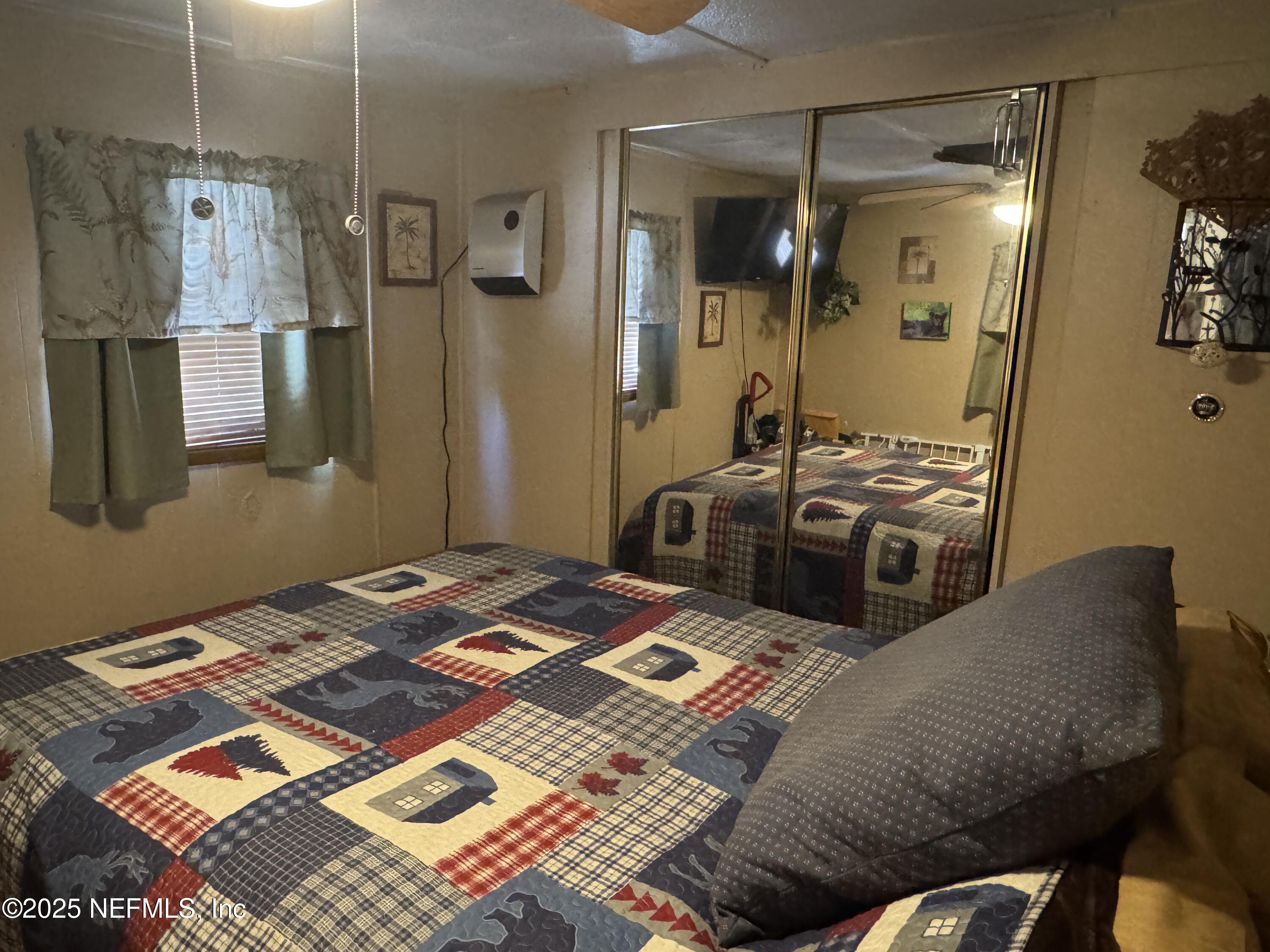 208 Lakeview Road Melrose, FL 32666 - Photo 13 of 22 a bed sitting in a room next to a lamp