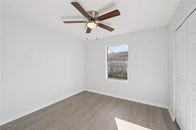 an empty room with wooden floor and ceiling fan