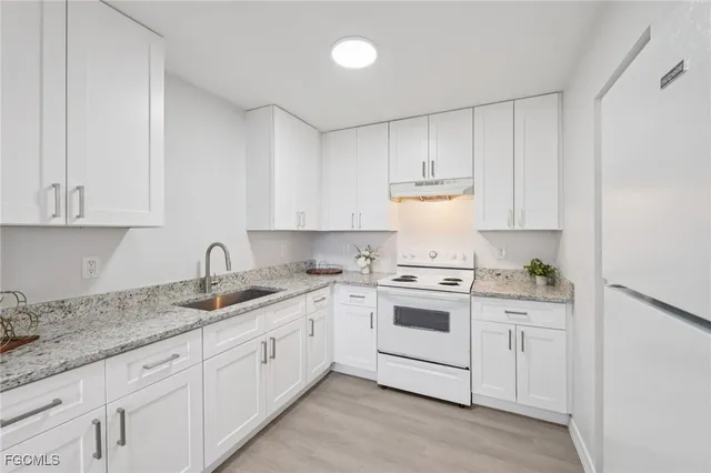 a kitchen with granite countertop white cabinets and white appliances