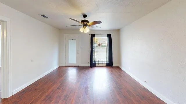 an empty room with wooden floor chandelier fan and closet in room