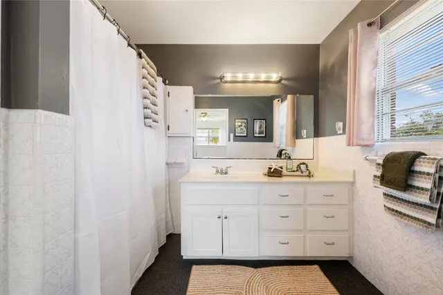 a bed sitting in a spacious bedroom next to a window and a chandelier