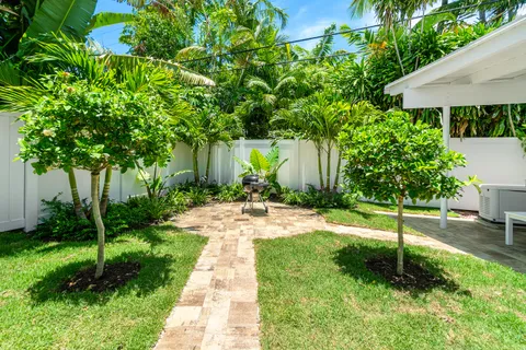 a view of a backyard with table and chairs potted plants and a palm tree