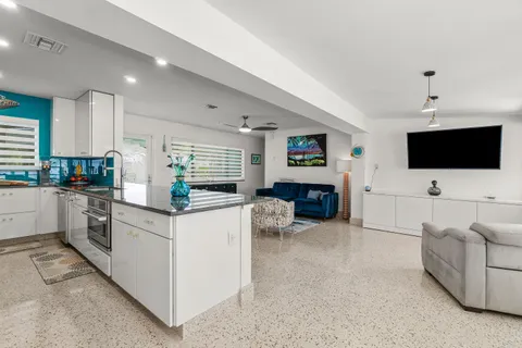 a kitchen with stainless steel appliances granite countertop a refrigerator a sink a stove a dining table and chairs