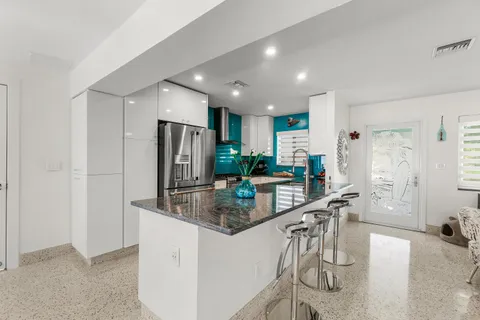 a large white kitchen with stainless steel appliances granite countertop a refrigerator and a sink