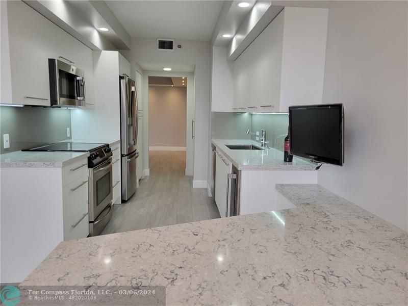 a kitchen with a sink a counter top space stainless steel appliances and cabinets