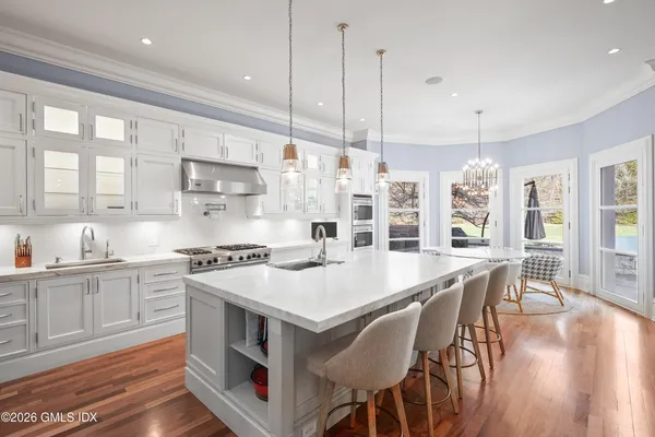a large kitchen with stainless steel appliances a stove a sink a center island and windows