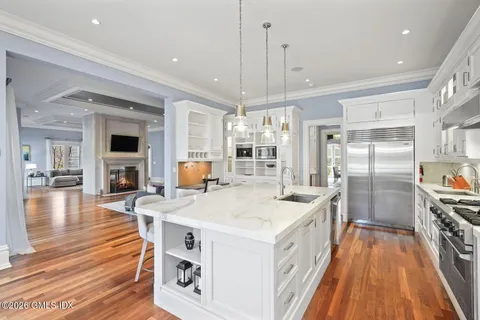 a large white kitchen with a center island wooden floor and stainless steel appliances