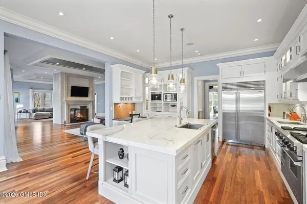 a large white kitchen with a center island wooden floor and stainless steel appliances