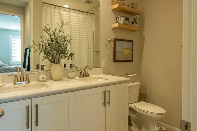 a bathroom with a granite countertop sink toilet and mirror
