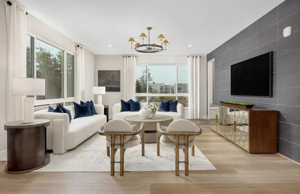 a living room with furniture a flat screen tv and large windows