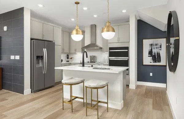 a kitchen with stainless steel appliances granite countertop a kitchen island a stove a refrigerator a sink a dining table and chairs with wooden floor