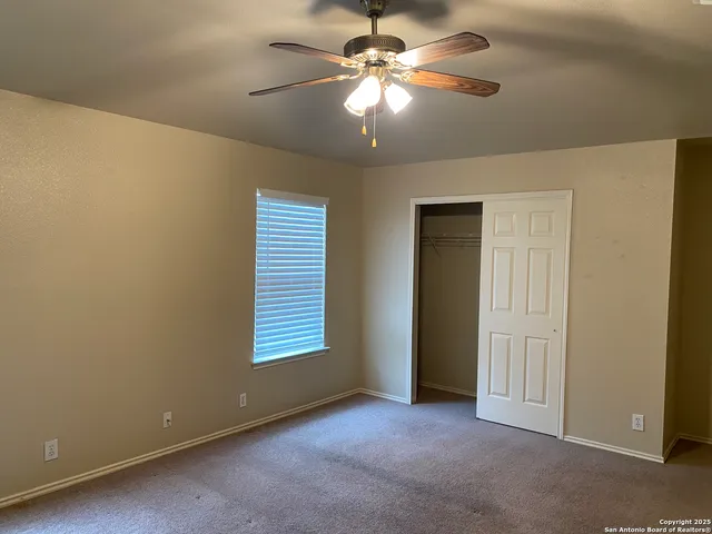 an empty room with a chandelier fan and closet area