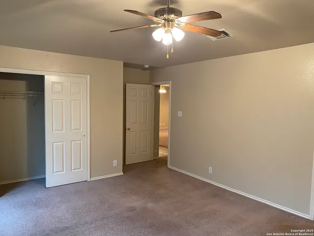 an empty room with a chandelier fan and closet