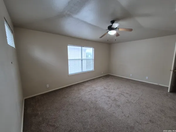 an empty room with windows and ceiling fan