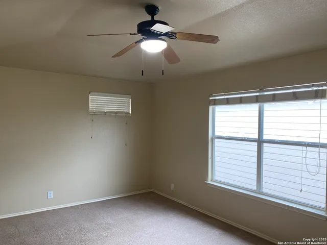 an empty room with a chandelier fan and windows