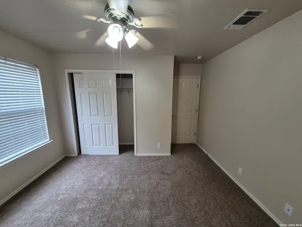 an empty room with a chandelier fan and windows