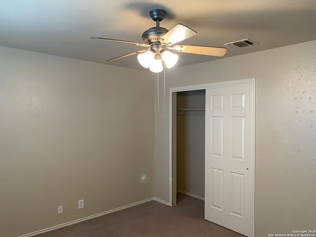 an empty room with a chandelier fan