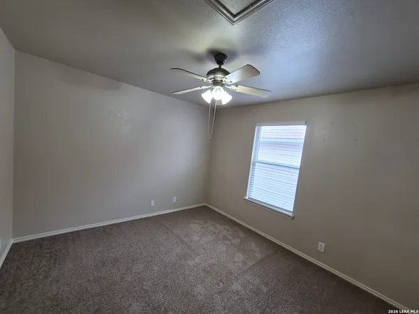 an empty room with windows and fan