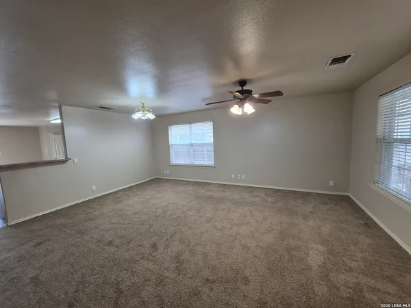 a view of an empty room with a chandelier fan