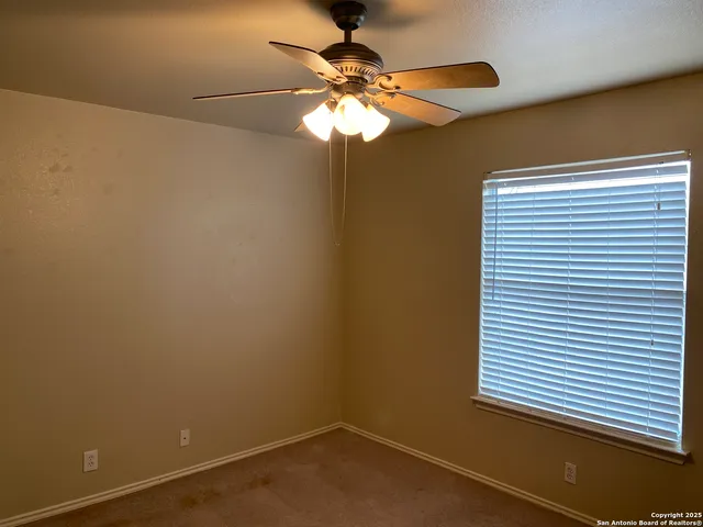 an empty room with a window and a fan