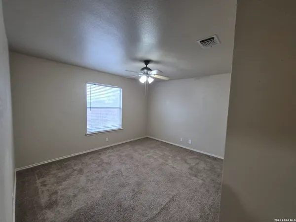 an empty room with a chandelier fan and windows
