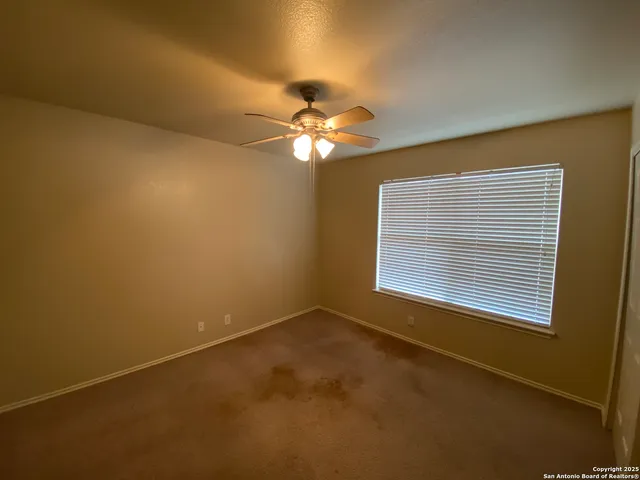 a view of a room with a chandelier fan and a window