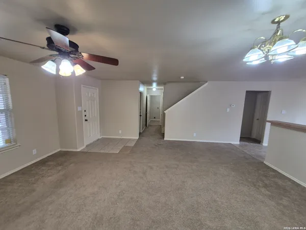 a view of an empty room with a chandelier fan