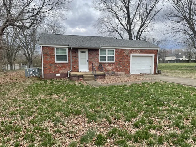a front view of a house with a garden and trees