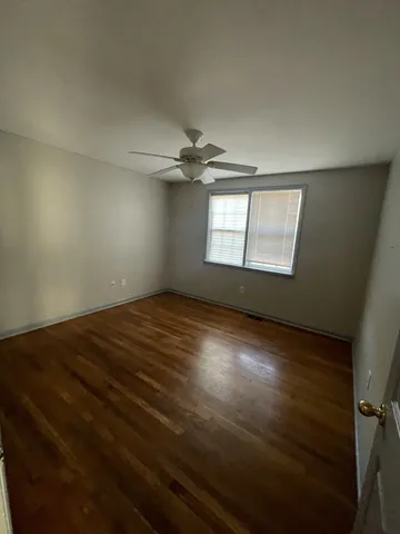 an empty room with wooden floor fan and windows