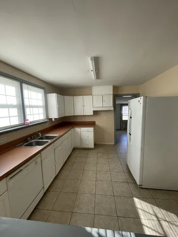 a large kitchen with a large counter top space a stove a refrigerator and cabinets