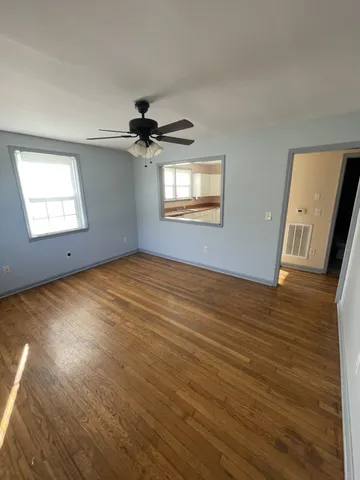 a view of an empty room with a window and wooden floor