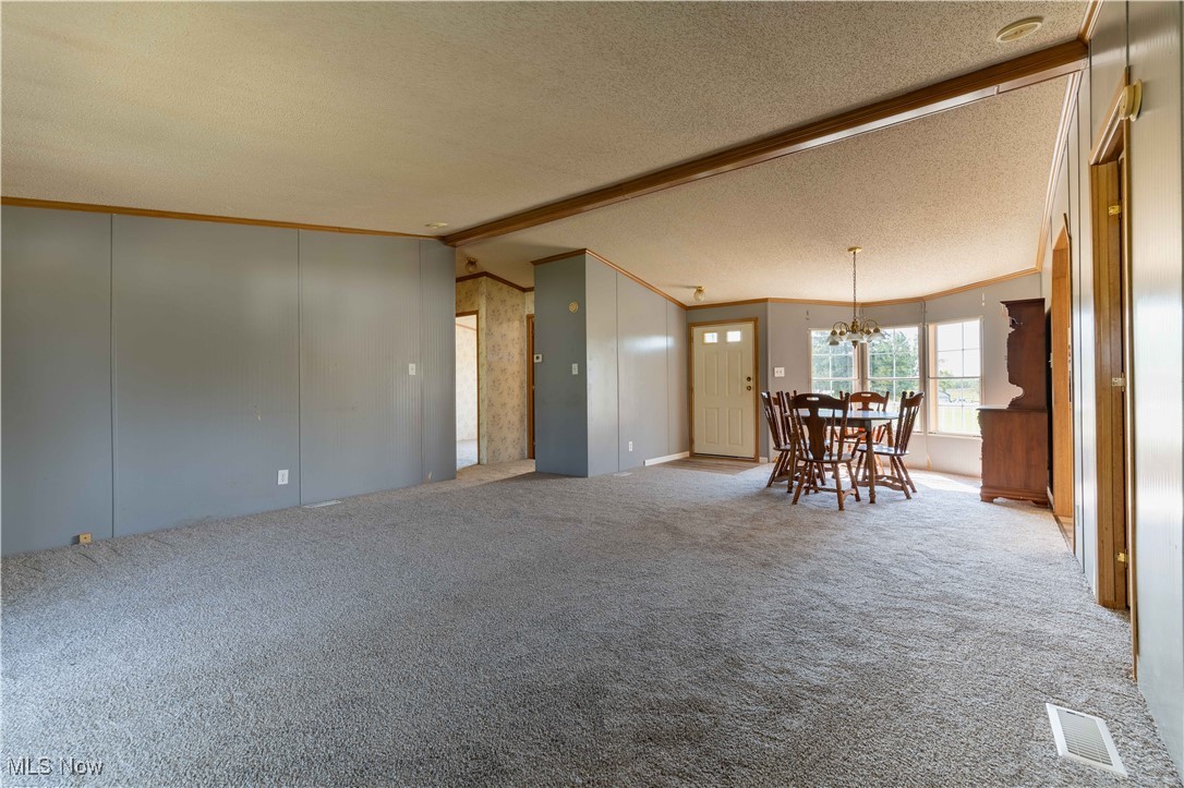 73550 Old Twenty One Road Kimbolton, OH 43749 - Photo 8 of 35 Living room featuring carpet floors, vaulted ceiling with beams, a textured ceiling, and a chandelier