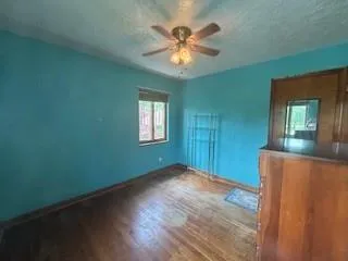 a view of an empty room with window and wooden floor