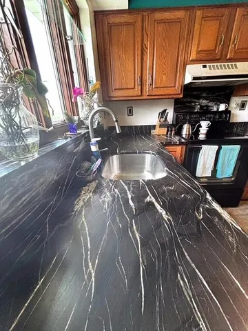 a kitchen with stainless steel appliances granite countertop a stove a sink and a microwave