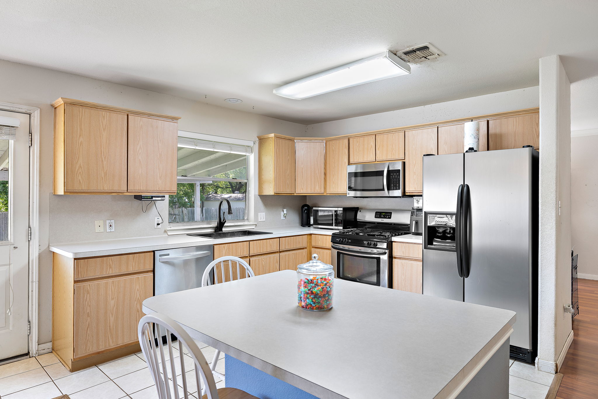 615 Runners Ridge Pflugerville, TX 78660 - Photo 12 of 32 a kitchen with stainless steel appliances granite countertop a microwave a stove a sink dishwasher a refrigerator with white cabinets and wooden floor
